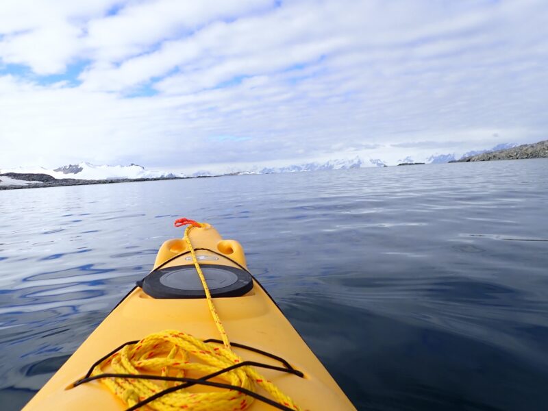 Point of view from kayak in Antarctica ocean with ice and mountains