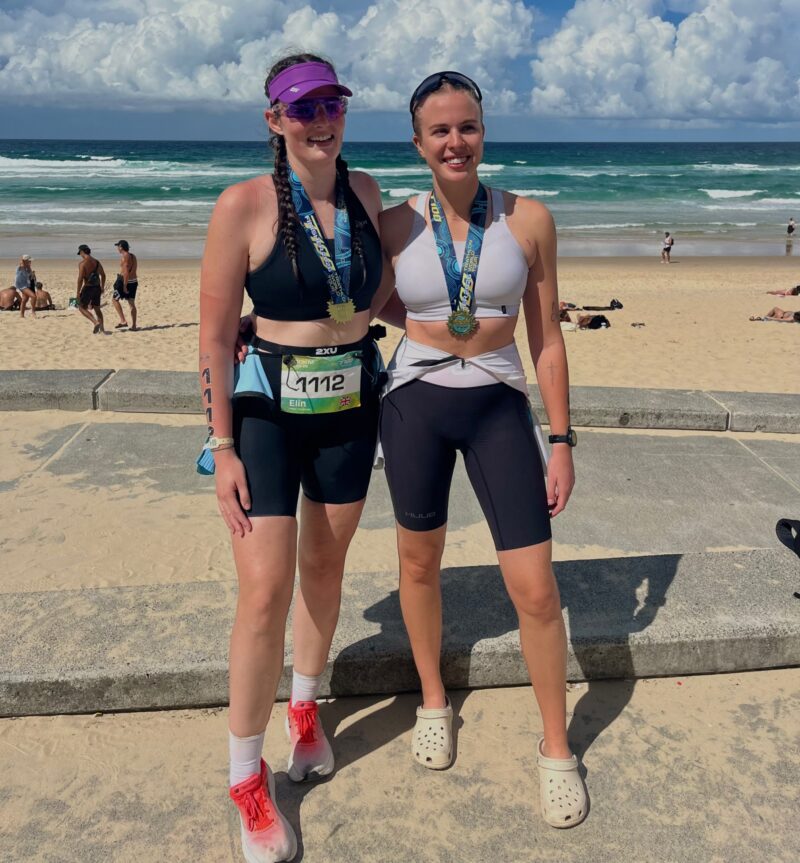 Sophie Dyer and fellow athlete with medals after completing T100 triathlon
