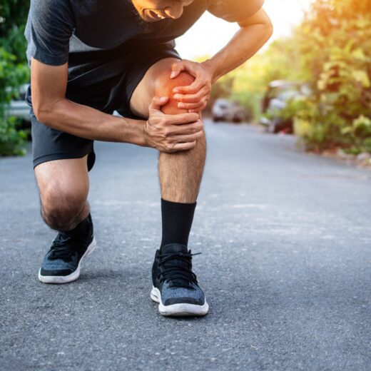 Runner experiencing knee pain during a run, illustrating common running injuries treated at PEAK Brisbane.