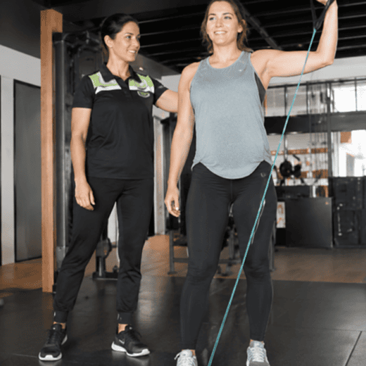 Women's Health Physiotherapist guiding a patient through a resistance band exercise during rehabilitation at PEAK Sports & Spine Centre.