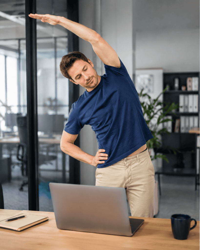 Man stretching beside his desk during a workday