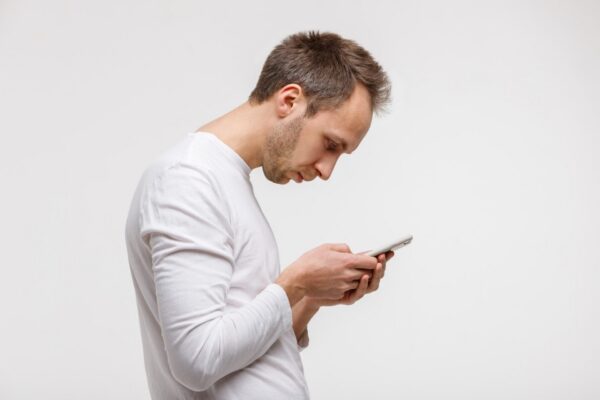 Man looking down at his smartphone with a rounded posture
